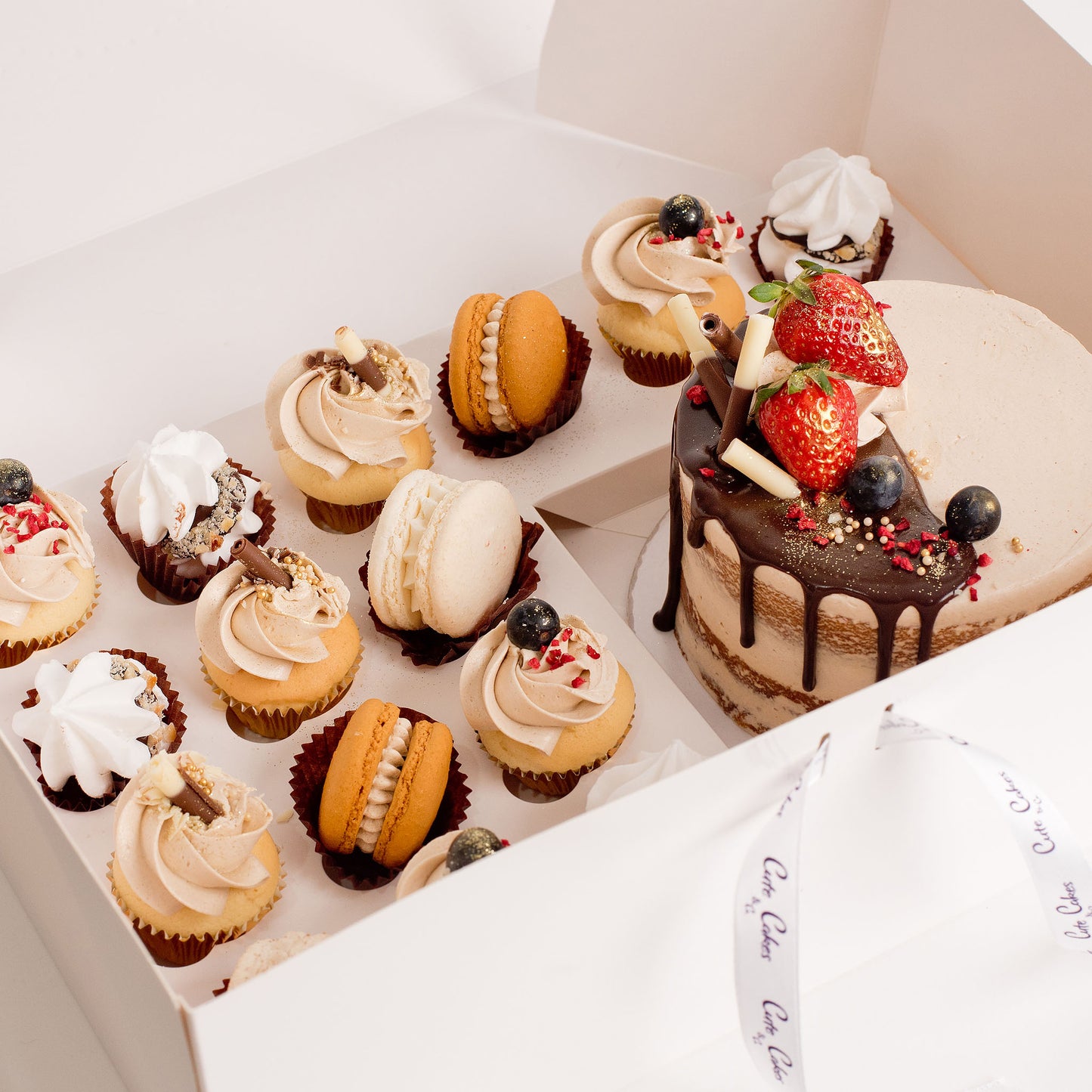 Cute cake and cupcake pack. Semi-naked caramel mini cake with gorgeous buttercream icing, seasonal fruit, chocolate sail and delicious dripping gold. Plus 7 mini cupcakes, 4 hazelnut kisses and 4 macarons. Ideal for work and corporate party celebrations. Cute Cakes & Co, Cute Cakes and Co, Brisbane online cake shop, mans birthday cake, Chocolate drip cake.