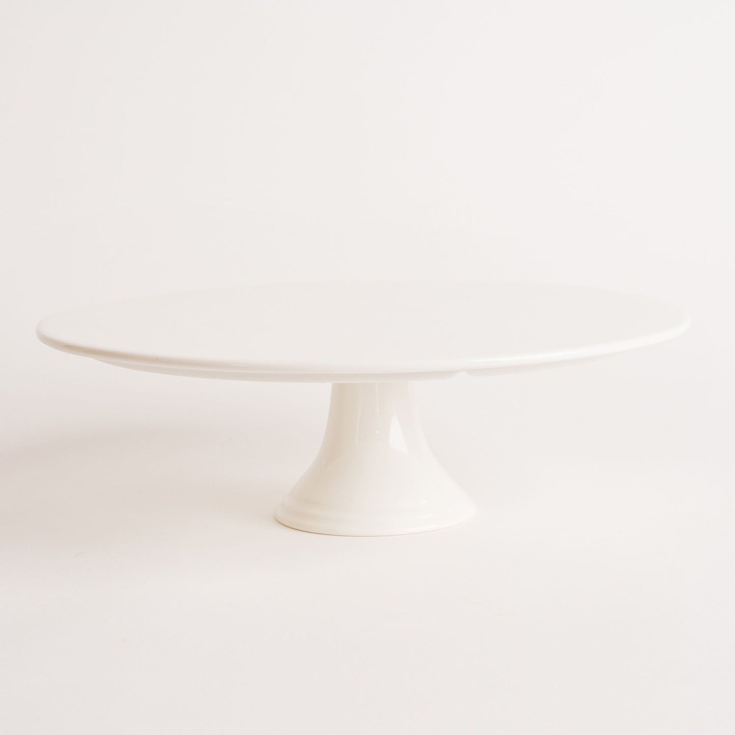 A white, round, single-tier porcelain cake stand with a flat surface and pedestal base. Beautiful birthday cakes and cupcakes, Cute Cakes and Co, Brisbane