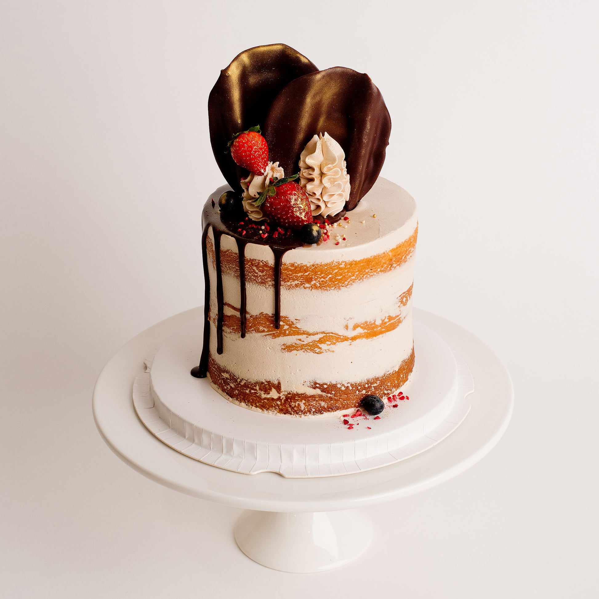 Semi-naked caramel layered cake looks and tastes gorgeous with its buttercream icing, seasonal fruit, chocolate sail and delicious dripping gold. Cute Cakes & Co, Cute Cakes and Co