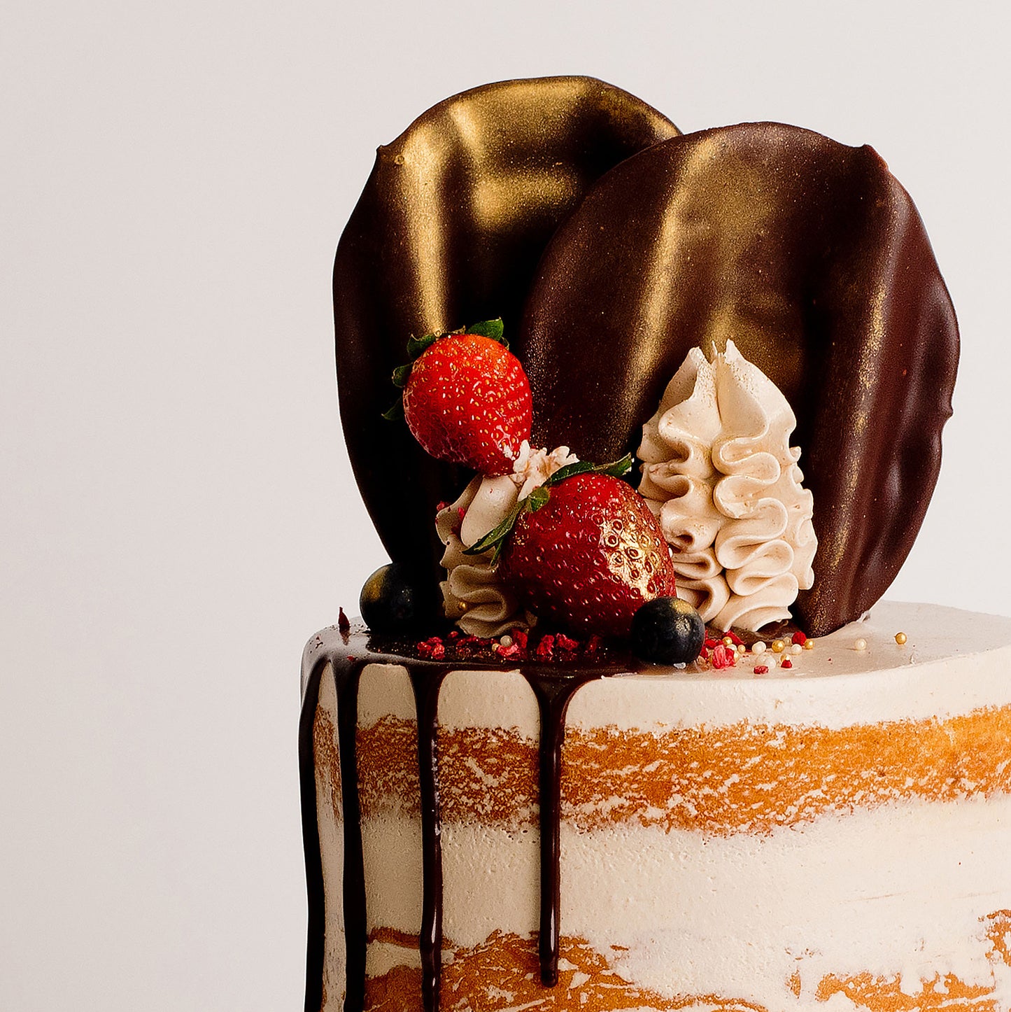 Semi-naked caramel layered cake looks and tastes gorgeous with its buttercream icing, seasonal fruit, chocolate sail and delicious dripping gold. Cute Cakes & Co, Cute Cakes and Co
