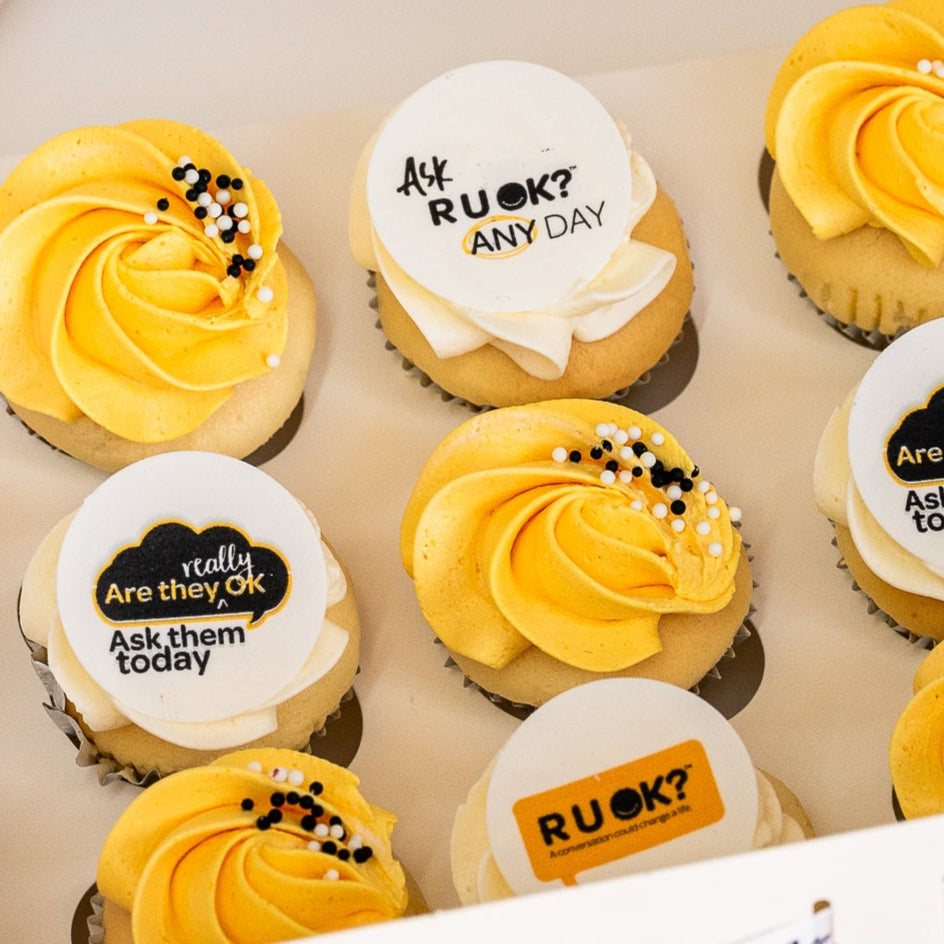 Mini cupcakes with yellow and white butterceam, some with black sprinkles and edible disks with 'R U OK?' text on them. RU Ok day, Cute Cakes and Co, Brisbane cake shop,