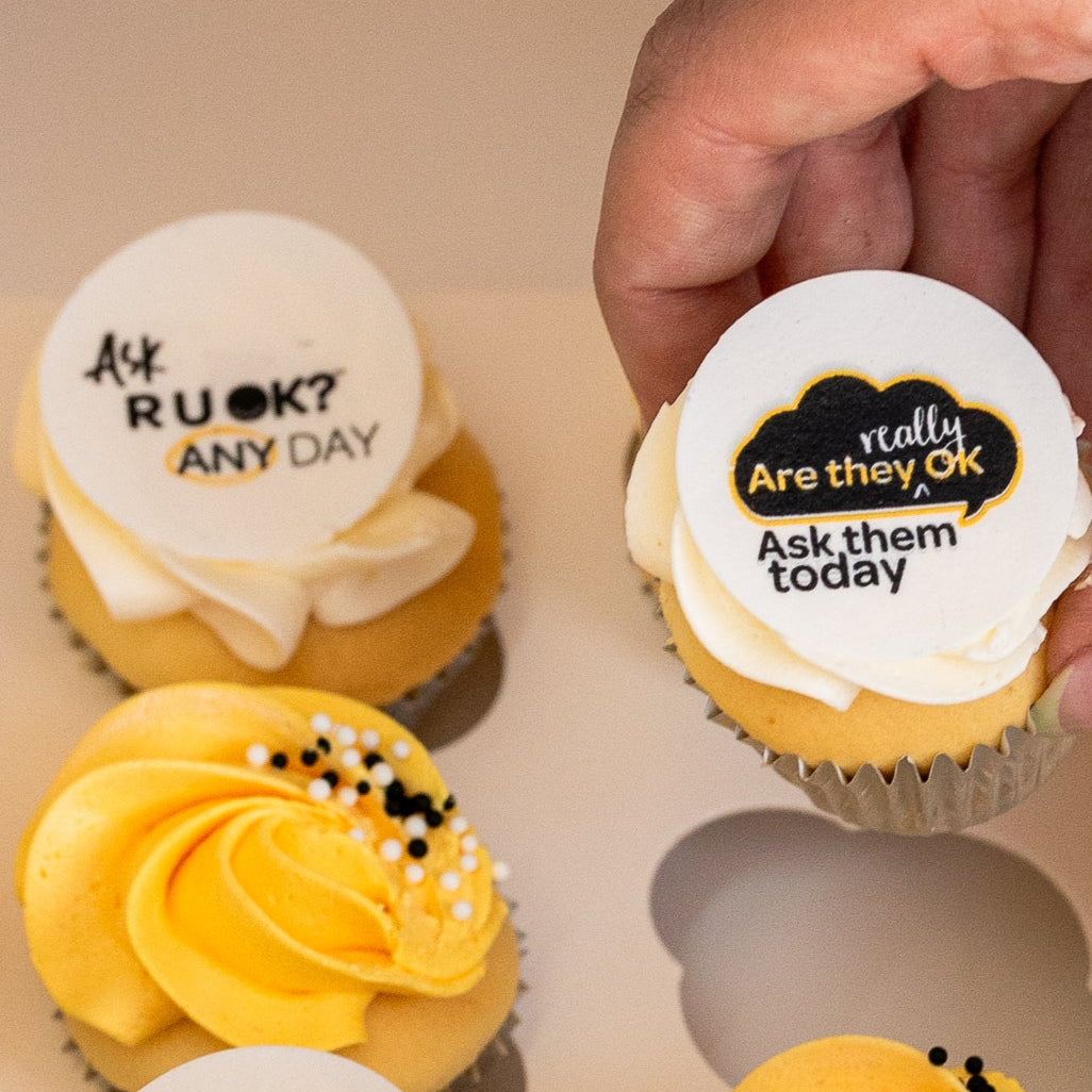 Mini cupcakes with yellow and white butterceam, some with black sprinkles and edible disks with 'R U OK?' text on them. RU Ok day, Cute Cakes and Co, Brisbane cake shop,