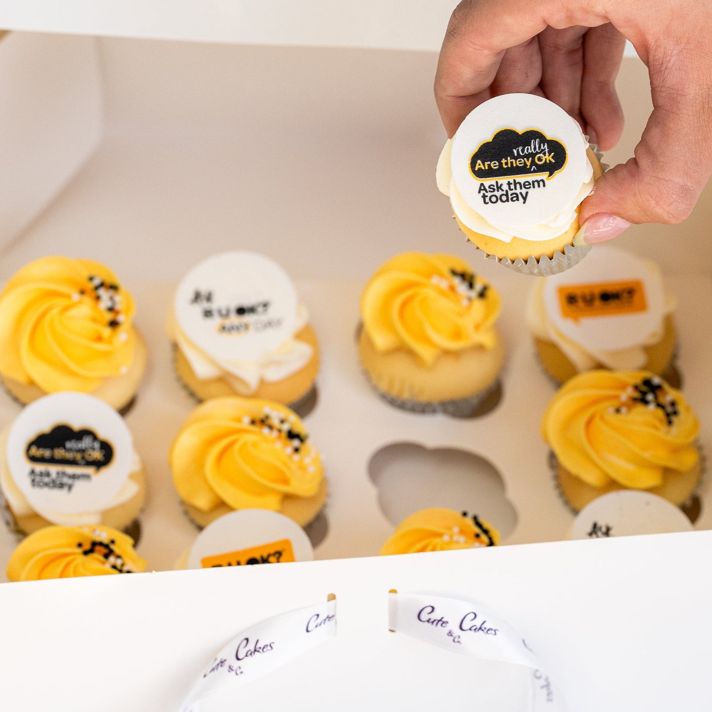 Mini cupcakes with yellow and white butterceam, some with black sprinkles and edible disks with 'R U OK?' text on them. RU Ok day, Cute Cakes and Co, Brisbane cake shop,