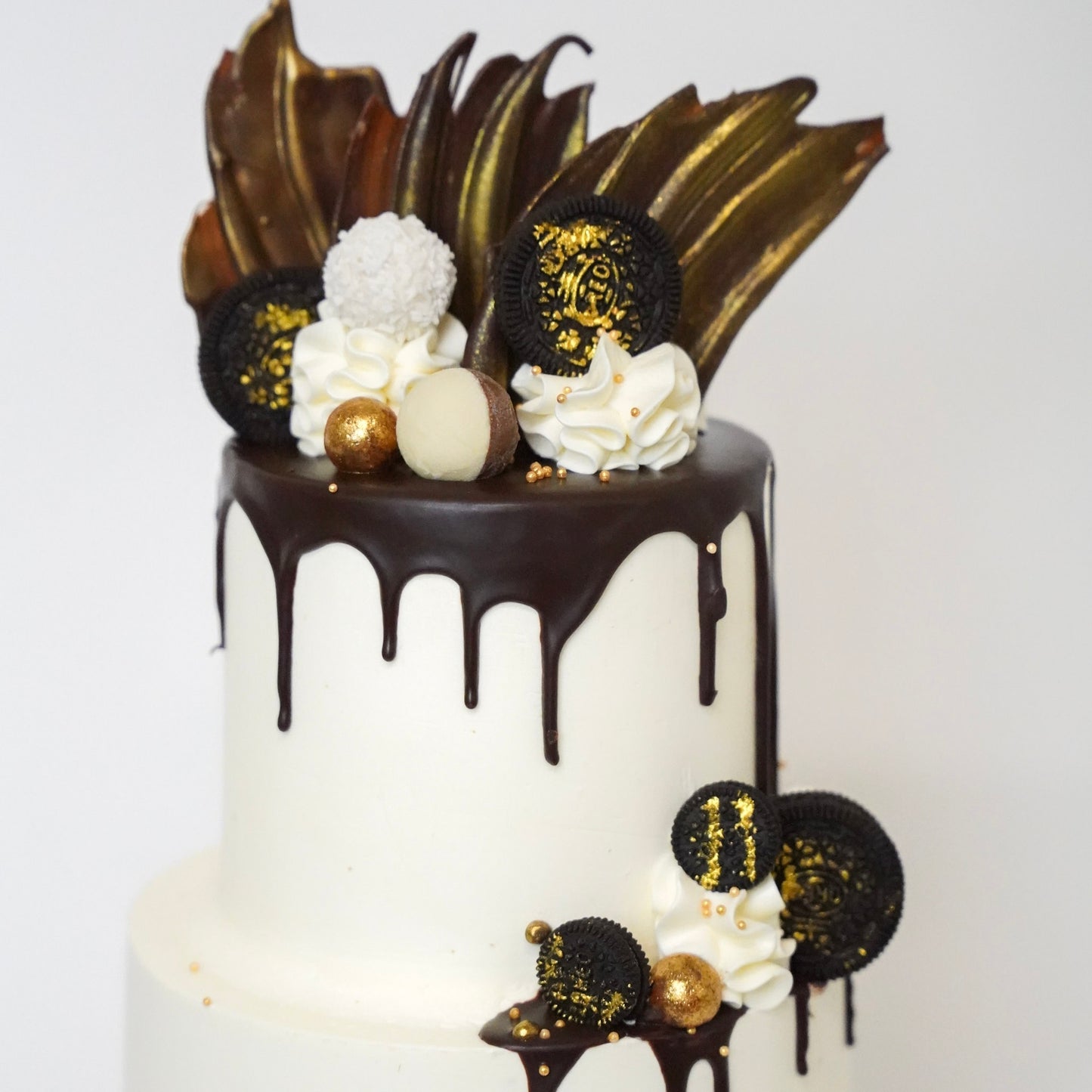 The Jo cake is generously covered with  luxurious buttercream and dripping of silky chocolate ganache drips down the sides, adding a touch of elegance and indulgence. Three golden chocolate sails stand tall on top of the cake, with Oreo Cookies, Raffaello chocolates, and Maltesers. Made by Cute Cakes & Co. 5 star cake shop in Brisbane 
Birthdays, anniversary weddings, gender reveal. 
Same day ordering available