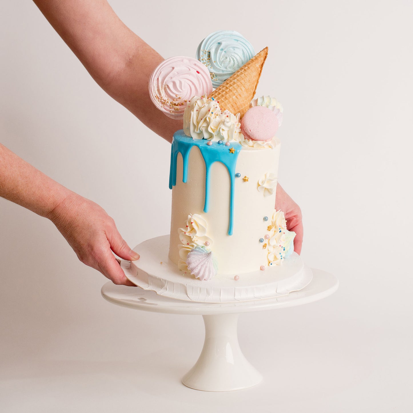 Beautiful pastel baby shower cake with pink and blue meringues being placed on a 12 inch white porcelain stand. birthday cakes and cupcakes, Cute Cakes and Co, Brisbane