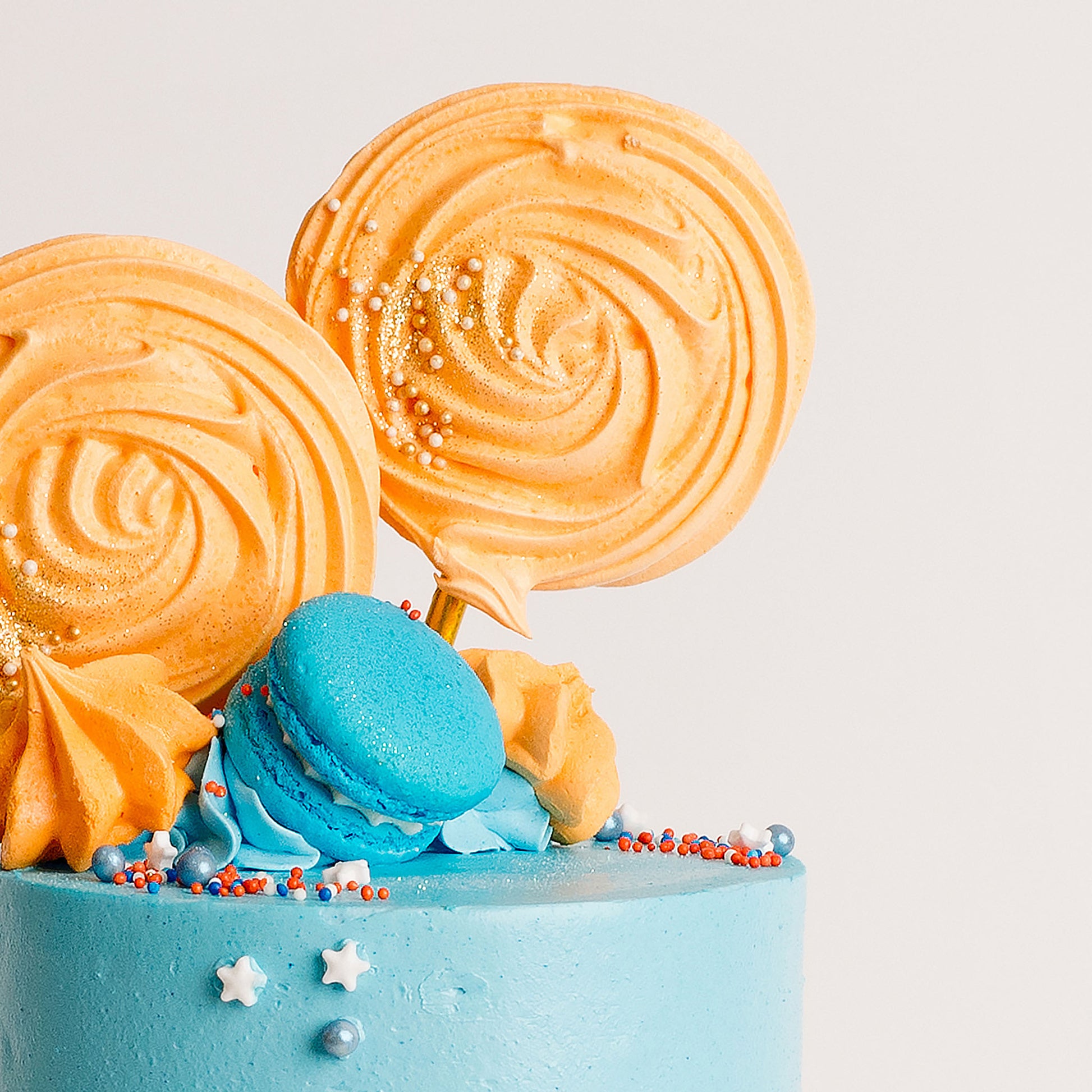 Fun blue and orange birthday cake with meringue pops and macarons, perfect to go with a bluey theme birthday party. Made by Cute Cakes & Co. 5 star rated cake shop in Brisbane.
