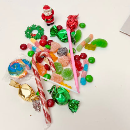 Assorted colorful candies on a white surface with a small Santa Claus figure.