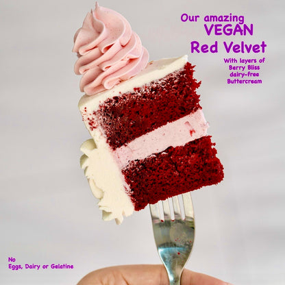 Slice of vegan red velvet cake with pink frosting on a fork against a gray background