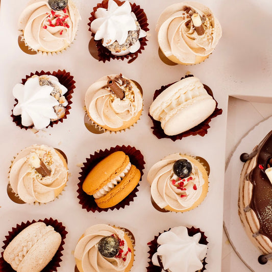 Assorted cupcakes with different frosting and toppings on a white surface.