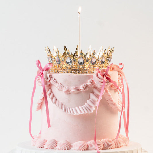 Vegan Pink Vintage style birthday cake. Pink ribbon bow with a crown on the top and candle. 