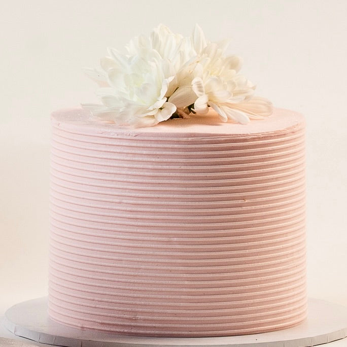 Light pink cake, decorated with ribbed buttercream feature on the sides and white fresh flowers on the top. Made with love by Brisbane’s favourite, 5 star cake shop, Cute Cakes & Co 