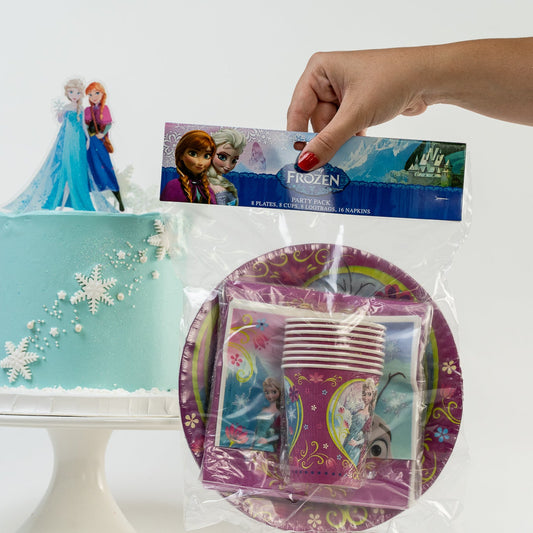 Frozen-themed party supplies including a cake, plates, and cups on a white background