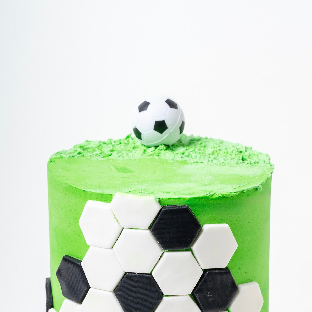 Soccer cake made with green buttercream with the soccer ball black-and-white pattern around the outside and a soccer ball on the top. Looks fabulous, Made with love by the five star cake shop ,Cute Cakes and Co, Brisbane. 