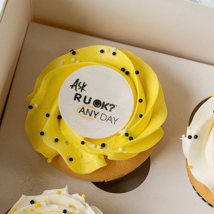 Single RU OK Day Cupcake with yellow &  buttercream topped with an edible disk that has 'Ask R U OK Any Day?' written on it.