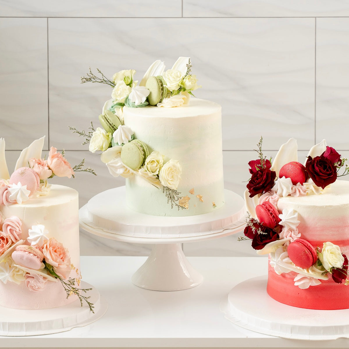 Three Cakes in the same design but in different colours. Pink, Greens and Red.