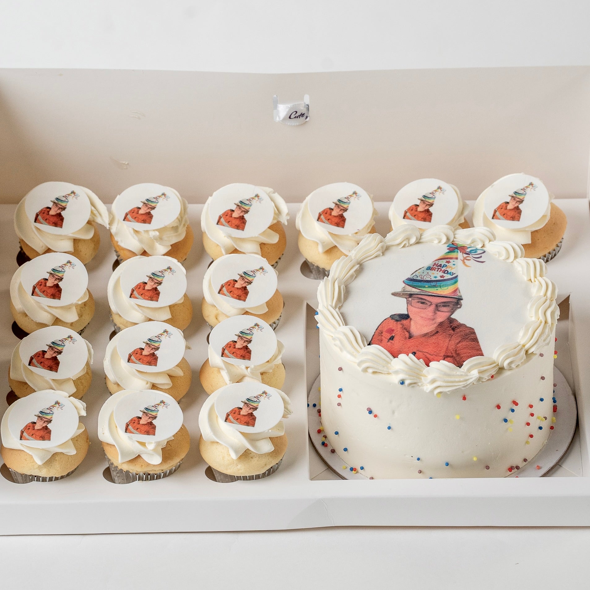 A custom birthday cake and matching mini cupcakes .The cake and cupcakes are decorated with white buttercream and topped with custom edible  toppers 