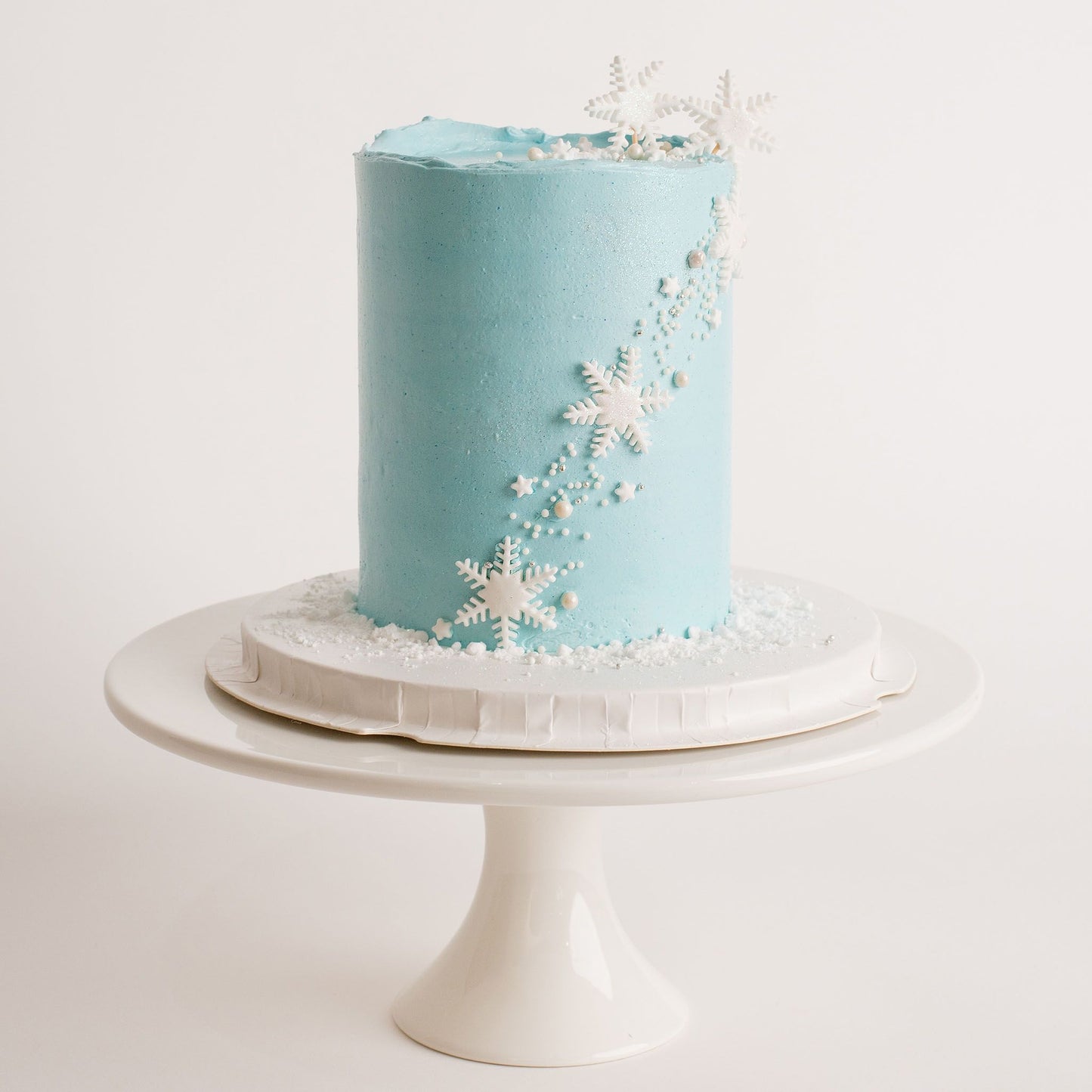 Disney Frozen themed birthday cake iced in light blue buttercream with snowflakes stars and glitter perfect for a little girl's birthday Looks fabulous.   Made with love by the five star cake shop ,Cute Cakes and Co, Brisbane.  Mitchelton , Cake shop near you 