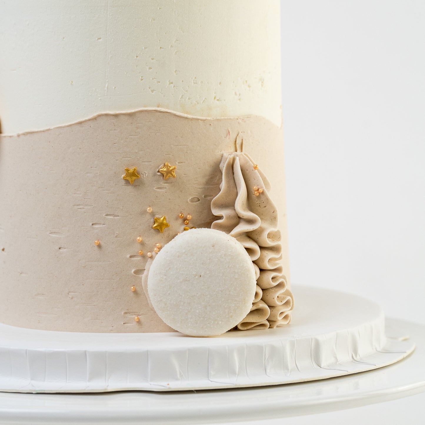 Close up shot of a white, caramel cake with gold balls and stars. Wiggle of buttercream at base and white Macaron. For perfect for engagements baby shower birthdays Looks fabulous, Made with love by Cute Cakes and Co. the 5 star review cake shop, in Brisbane.