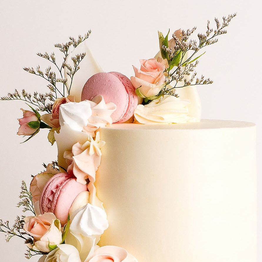 Decorative cake with flowers and macarons on a white background