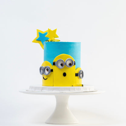 Minion birthday cake. Decorated with blue buttercream, three Despicable Me minions  characters on the front with icing bananas and stars as decoration.  Looks fabulous, Made with love by Cute Cakes and Co. the 5 star review cake shop, in Brisbane.