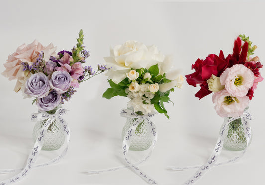 Three different petite posy flower arrangements in vases, with each arrangement consisting of a variety of flowers in different colors.