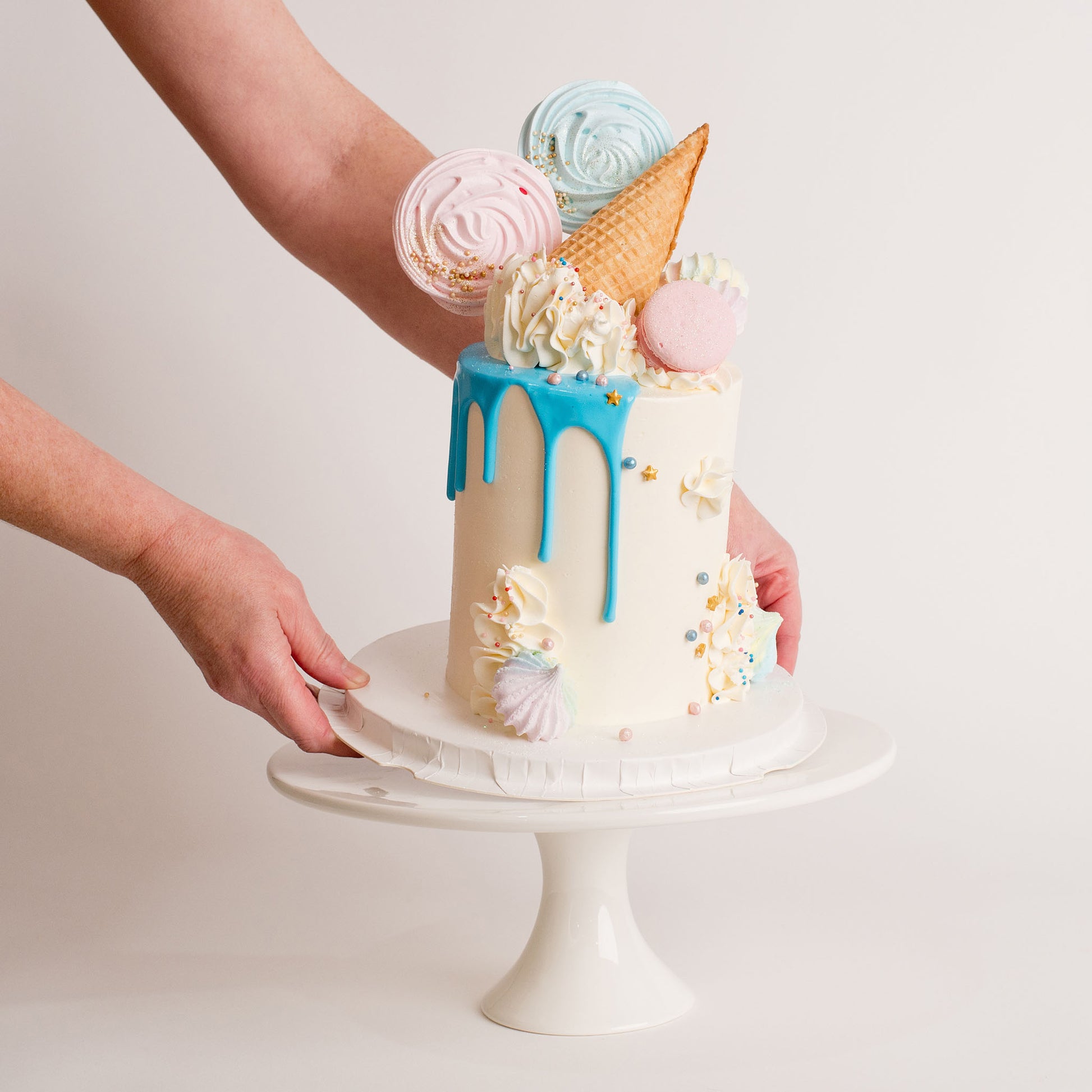 Beautiful pastel baby shower cake with pink and blue meringues being placed on a 12 inch white porcelain stand. birthday cakes and cupcakes, Cute Cakes and Co, Brisbane 