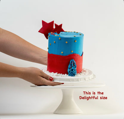 Hands placing down the Superhero themed cake blue and red buttercream gold stars  Made with love by Cute Cakes & Co, Brisbane Favourite cake shop. 
5 star review cake shop in Brisbane. 