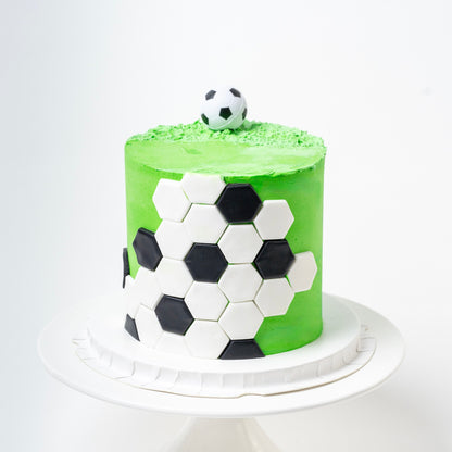 Soccer cake made with green buttercream with the soccer ball black-and-white pattern around the outside and a soccer ball on the top. Looks fabulous, Made with love by the five star cake shop ,Cute Cakes and Co, Brisbane. 