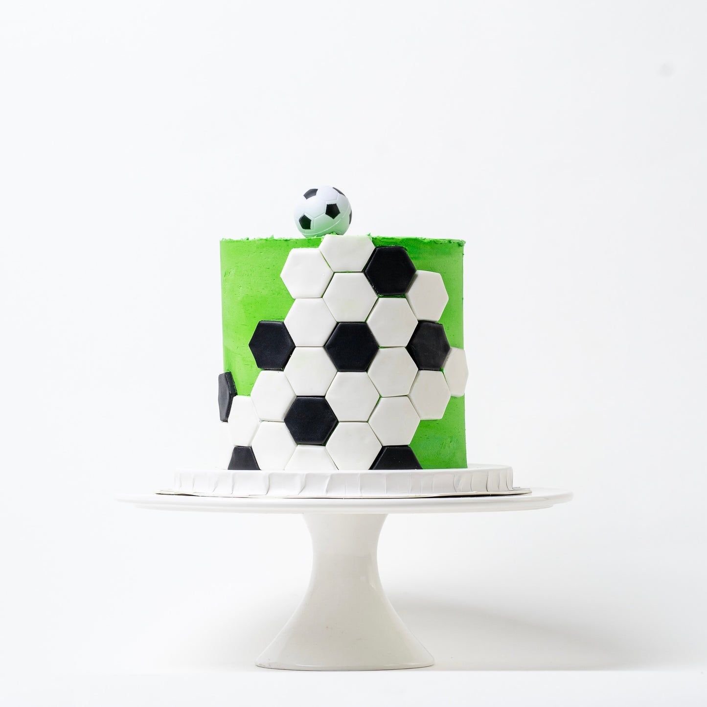 Soccer cake made with green buttercream with the soccer ball black-and-white pattern around the outside and a soccer ball on the top. Looks fabulous, Made with love by the five star cake shop ,Cute Cakes and Co, Brisbane. 