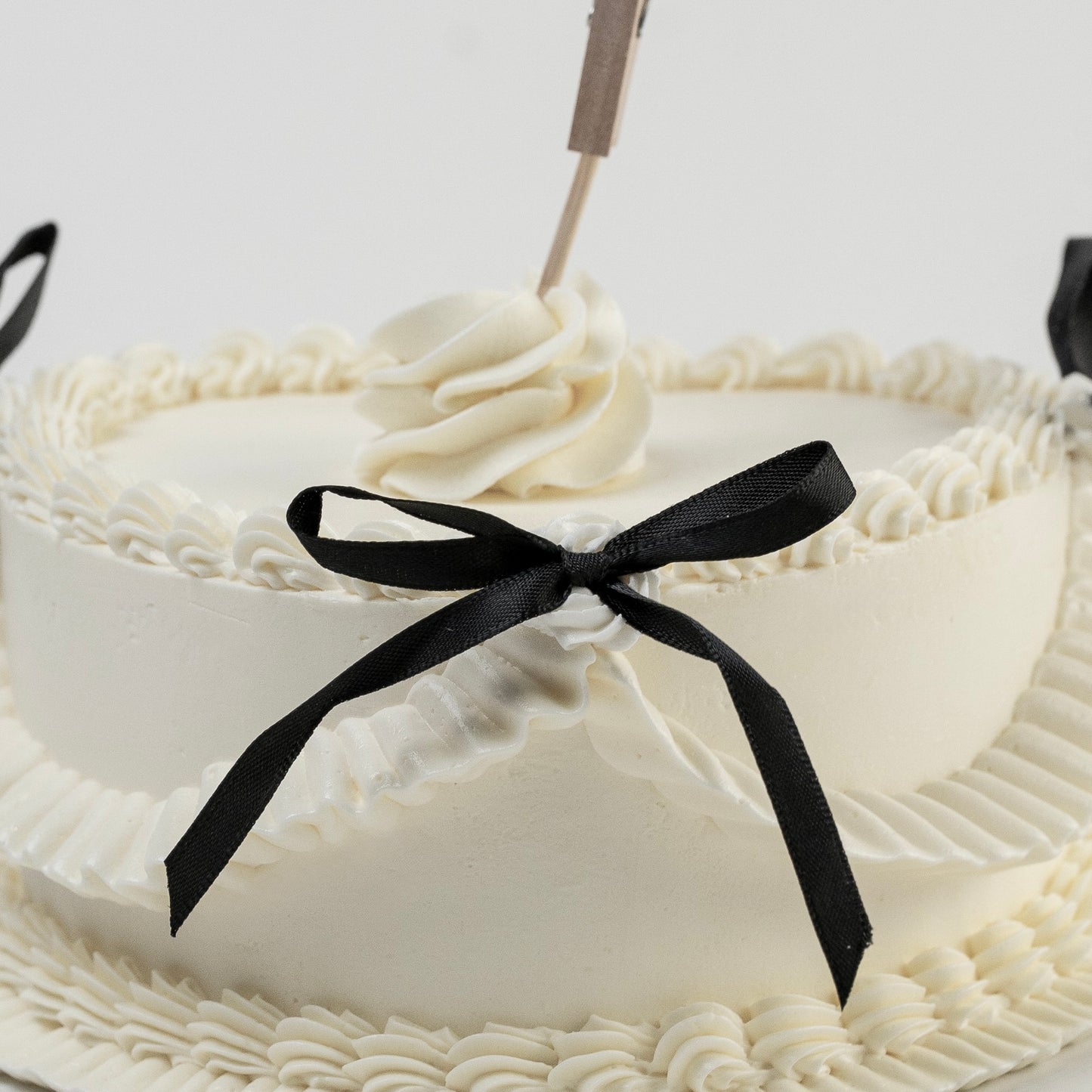 Close up of piping of a white Vintage style cake with black ribbons and a Polaroid photo ultrasound photo Perfect for baby announcement . Made with love by Cute Cakes and Co. the 5 star cake shop, in Brisbane.