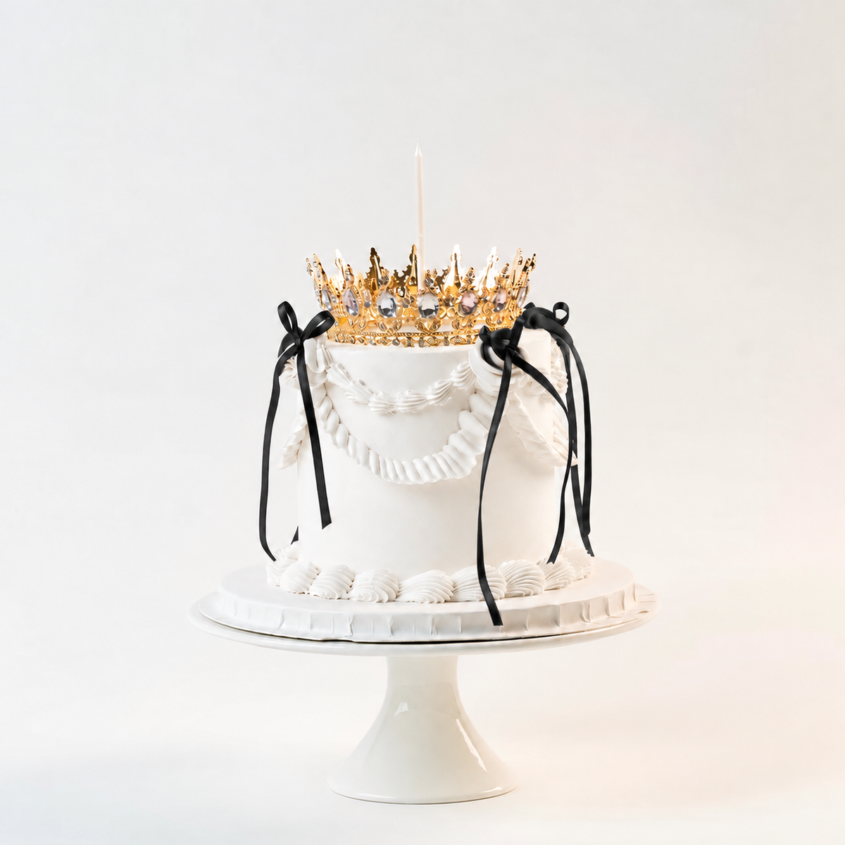 White Vintage style birthday cake. Black ribbon bow with a crown on the top and candle.