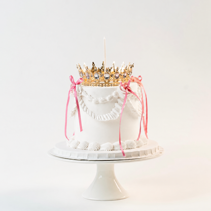 White  Vintage style  cake. Pink ribbon bow with a crown on the top and candle.