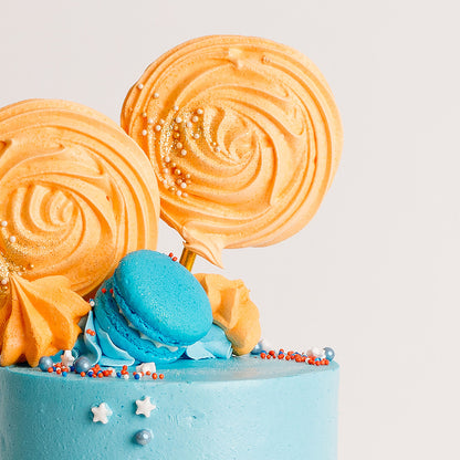 Fun blue and orange birthday cake with meringue pops and macarons, perfect to go with a bluey theme birthday party. Made by Cute Cakes & Co. 5 star rated cake shop in Brisbane. 