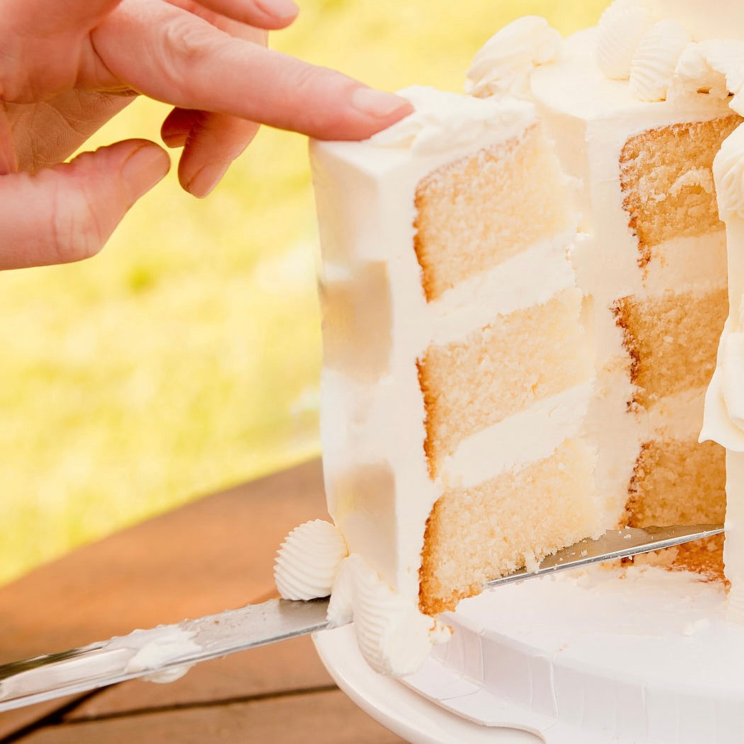 Close-up of a slice of layered cake being cut with a hand and knife, 