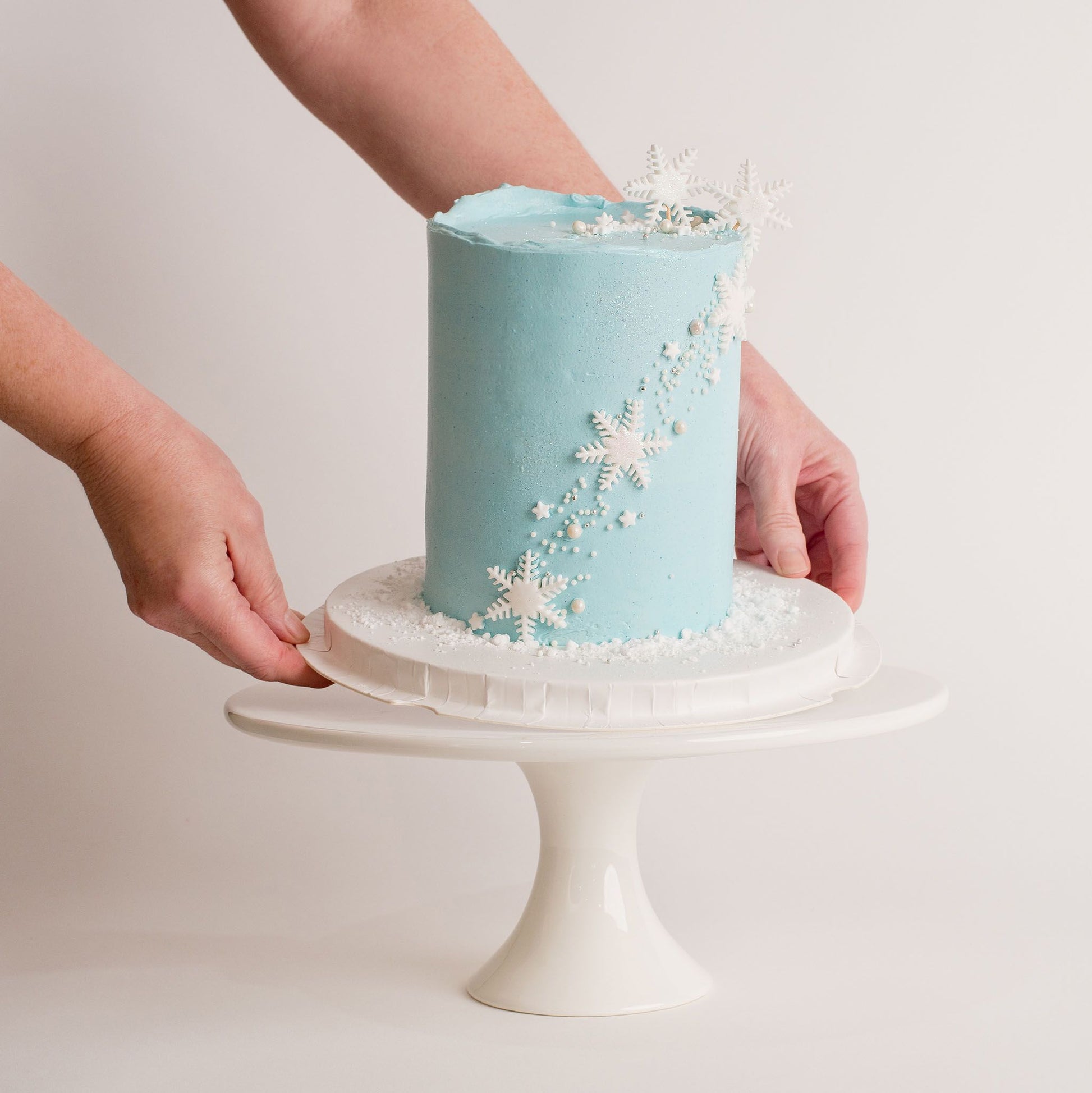 Disney Frozen themed birthday cake being placed on a cake.  iced in light blue buttercream with snowflakes stars and glitter perfect for a little girl's birthday Looks fabulous.   Made with love by the five star cake shop ,Cute Cakes and Co, Brisbane.  Mitchelton , Cake shop near you 