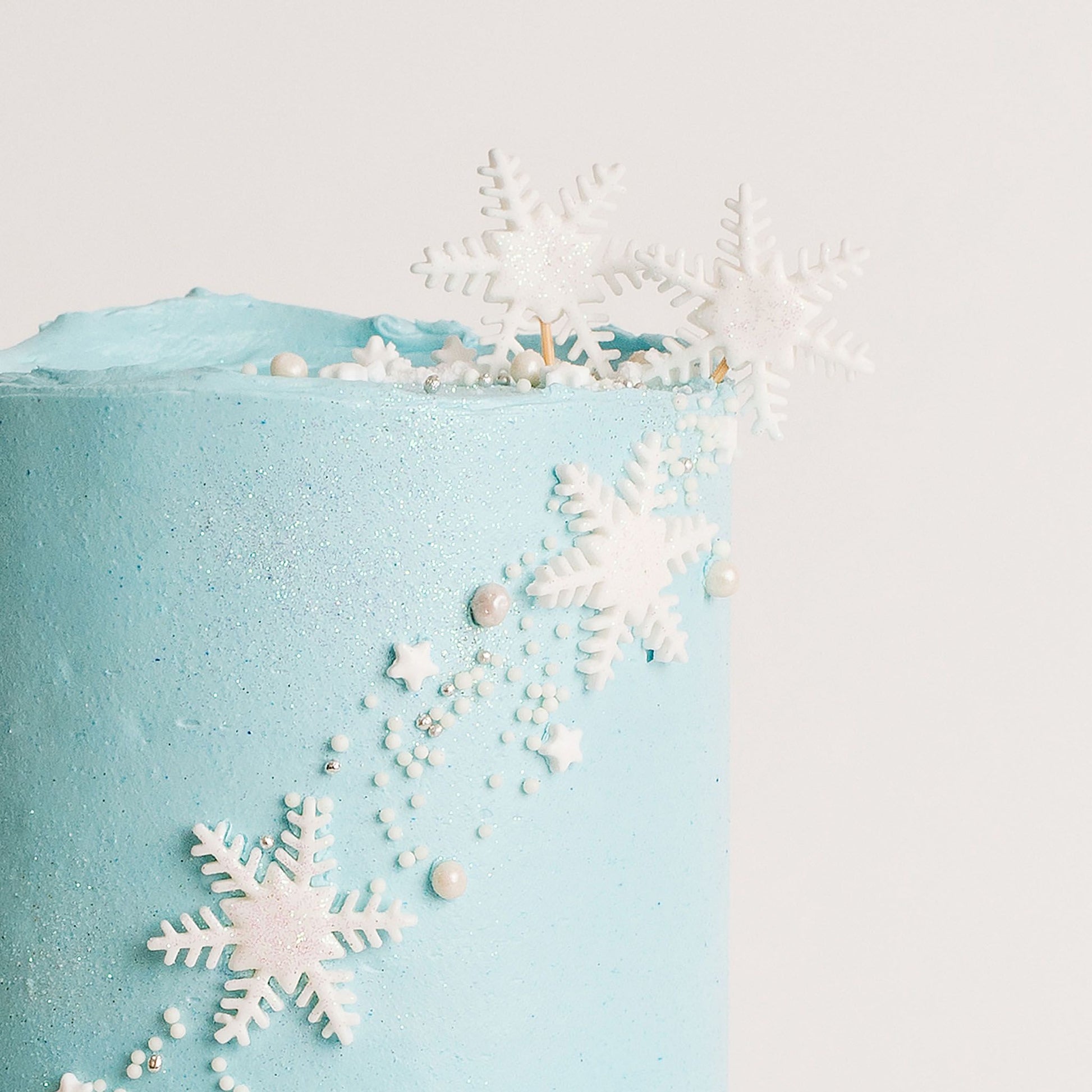 Disney Frozen themed birthday cake iced in light blue buttercream with snowflakes stars and glitter perfect for a little girl's birthday Looks fabulous.   Made with love by the five star cake shop ,Cute Cakes and Co, Brisbane.  Mitchelton , Cake shop near you 