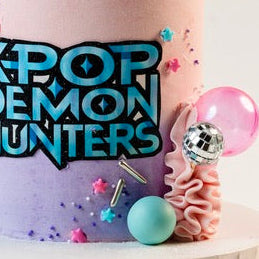 K-pop Demon Hunters birthday cake. 
Pink, Blue and purple buttercream and decorations. With disco balls. K-Pop Demon Hunters logo at the front. Made with love by Brisbane’s favourite, 5 star cake shop, Cute Cakes & Co 