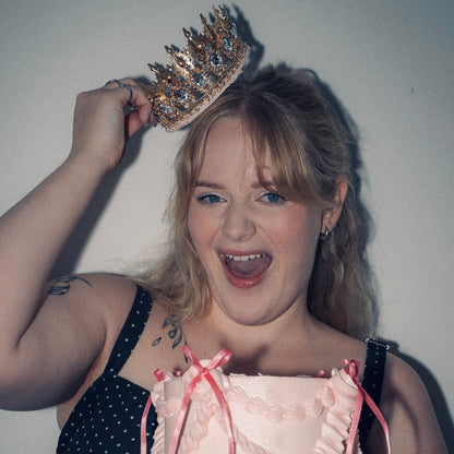 woman holding a gold crown from a pink Vintage style birthday cake. Pink ribbon bow 
Made with love by Brisbane’s favourite, 5 star cake shop, Cute Cakes & Co cake 