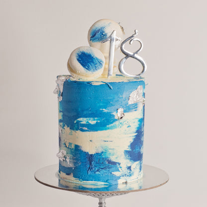 Blue birthday cake with silver leaf, white macarons and soft buttercream texture with 18 topper 