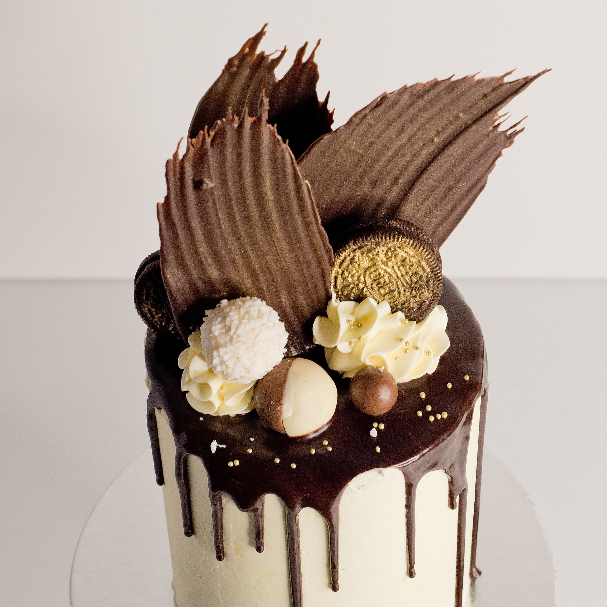 Close-up of Jo Blanc cake with ganache drip, Oreos and gold decorations